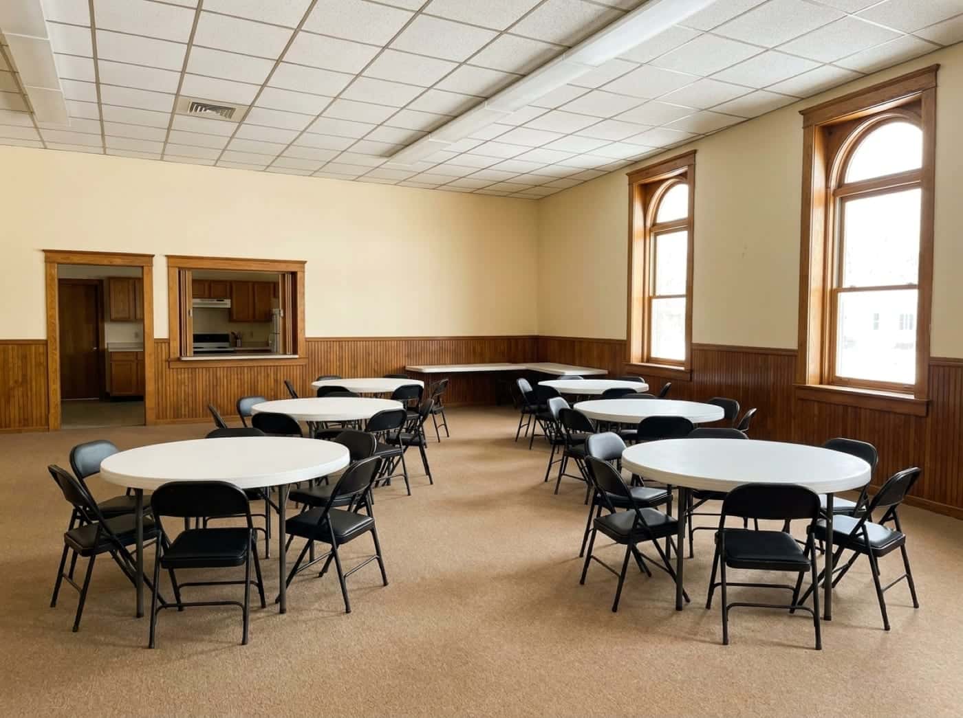 A spotless community hall set with round tables before an event